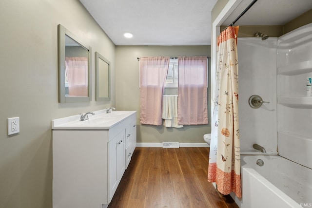 full bathroom featuring hardwood / wood-style flooring, shower / tub combo with curtain, vanity, and toilet