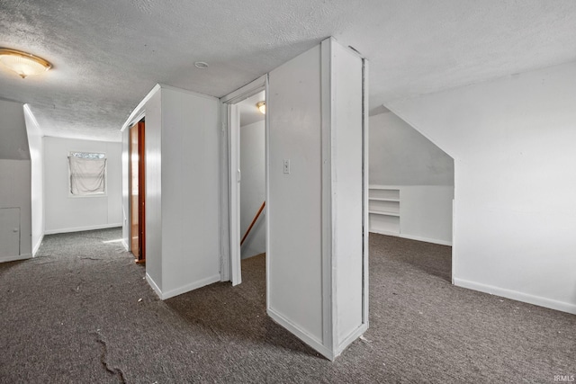 hallway featuring dark colored carpet and a textured ceiling