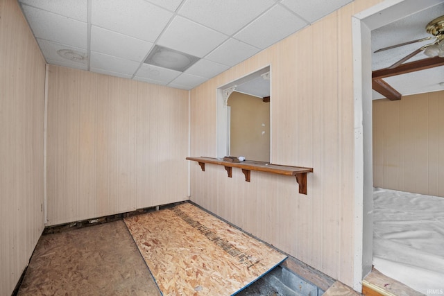 spare room featuring a drop ceiling and wood walls