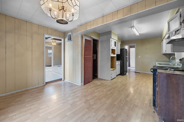 kitchen with white cabinetry, stove, black refrigerator, and light hardwood / wood-style flooring