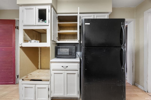 kitchen with light hardwood / wood-style flooring, white cabinets, and black appliances