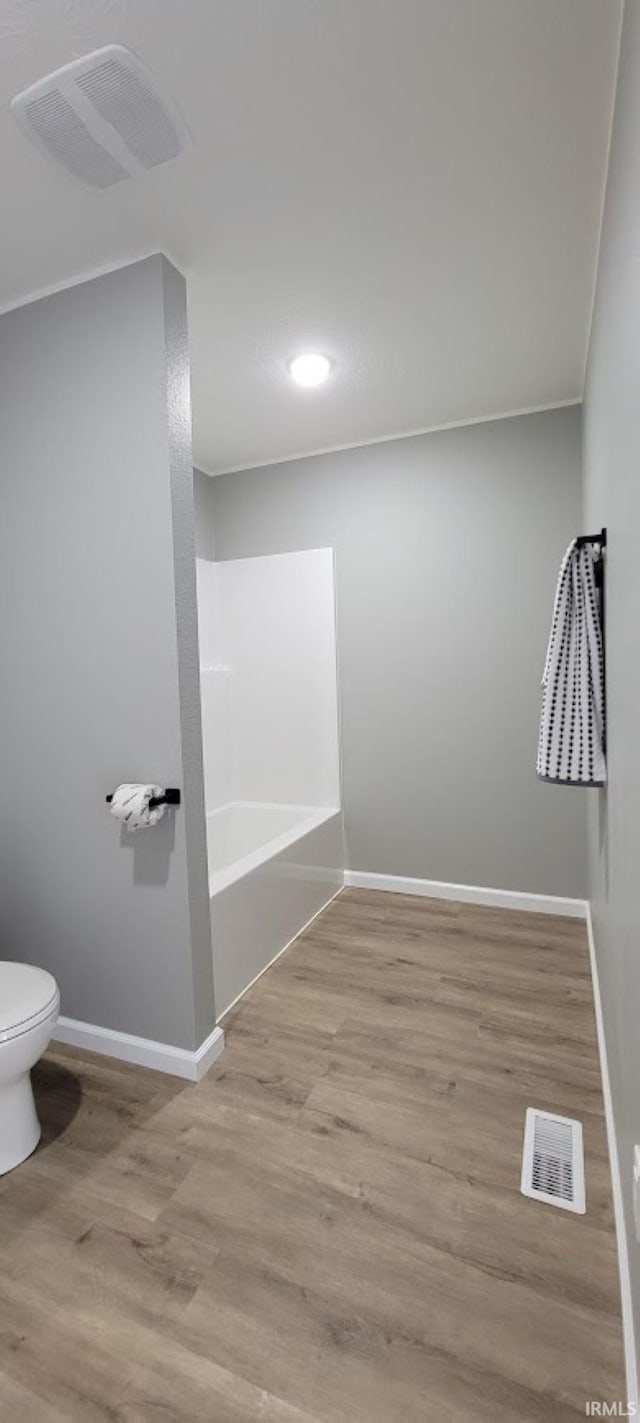 bathroom with hardwood / wood-style flooring, ornamental molding, tub / shower combination, and toilet