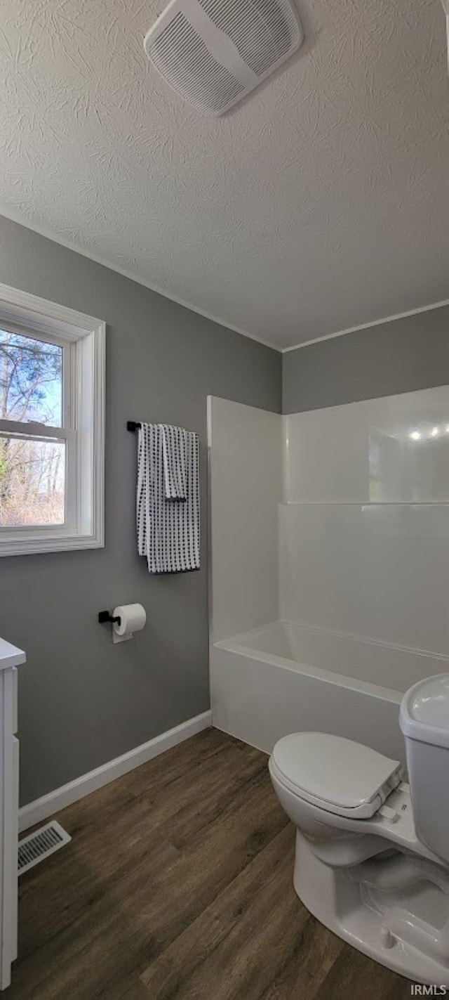 full bathroom with hardwood / wood-style floors, vanity, toilet, bathing tub / shower combination, and a textured ceiling