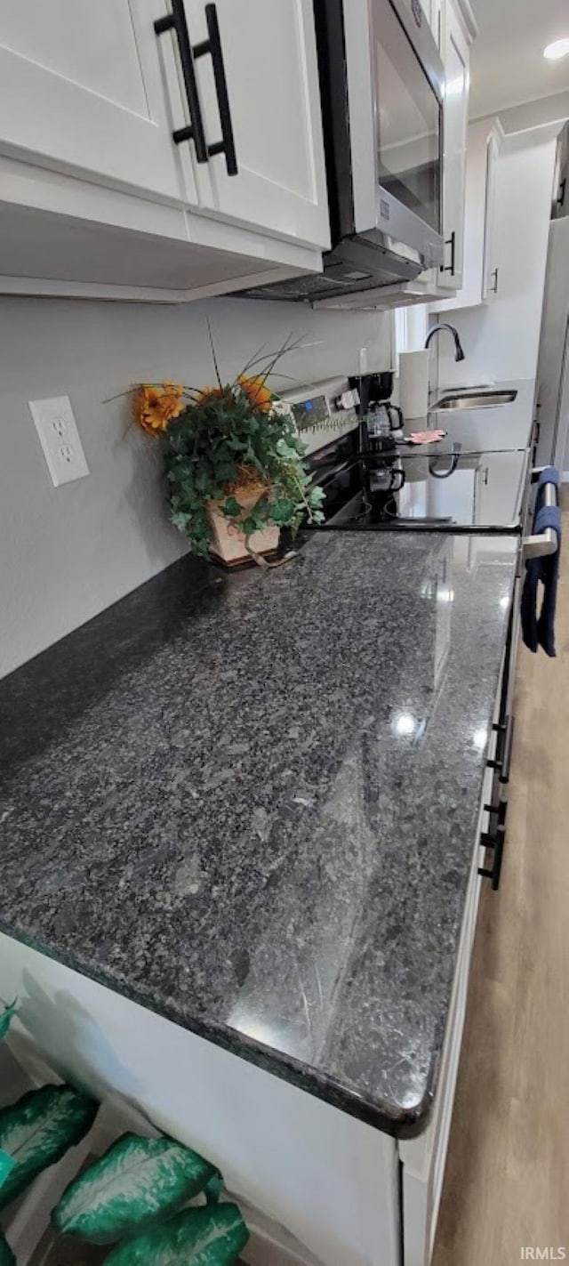 interior space featuring white cabinetry, dark stone counters, sink, and light hardwood / wood-style flooring