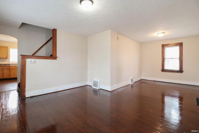 empty room featuring dark hardwood / wood-style flooring, a wealth of natural light, and a textured ceiling