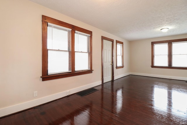 empty room featuring dark hardwood / wood-style flooring and a textured ceiling