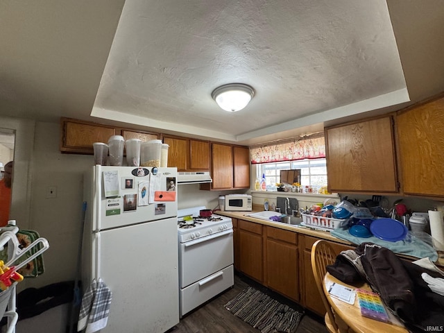 kitchen featuring a tray ceiling, white appliances, dark wood-type flooring, and a textured ceiling