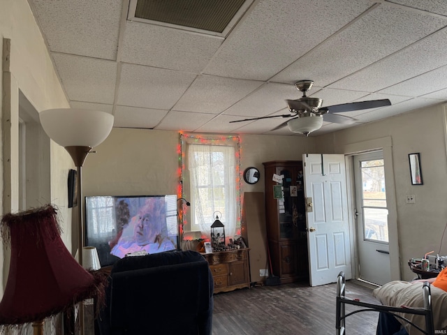 living room featuring a drop ceiling, dark wood-type flooring, and ceiling fan