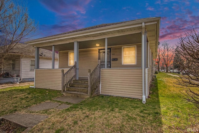 bungalow-style home with a lawn and covered porch