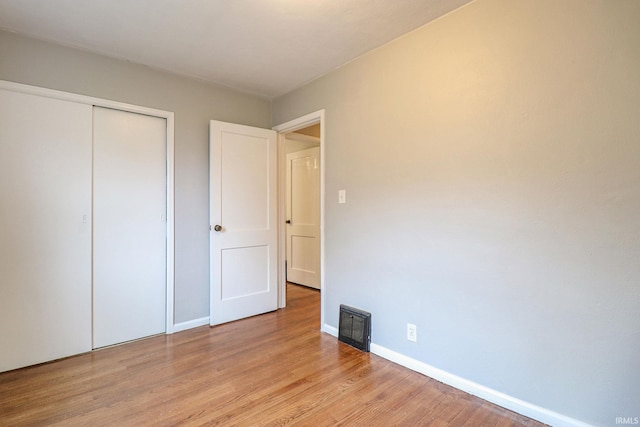 unfurnished bedroom with light wood-type flooring and a closet