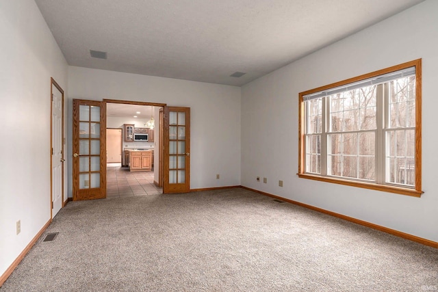 carpeted empty room featuring french doors and a textured ceiling