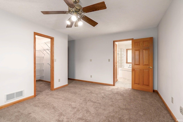 unfurnished bedroom with connected bathroom, light carpet, and ceiling fan