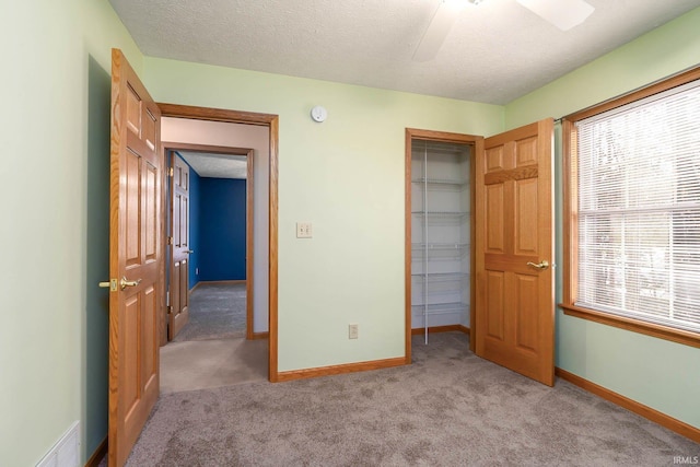 carpeted bedroom with ceiling fan, a closet, and a textured ceiling