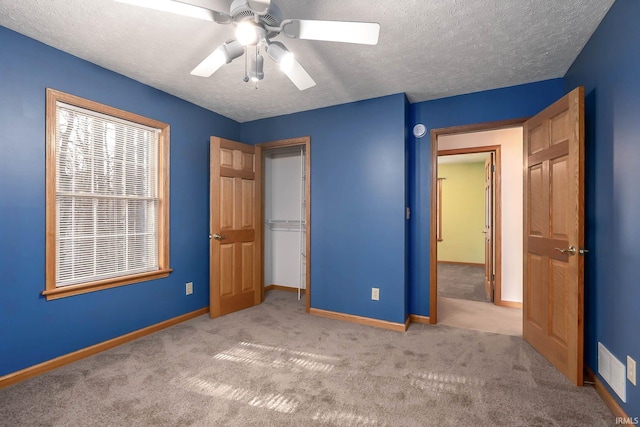 unfurnished bedroom featuring ceiling fan, light colored carpet, and a textured ceiling