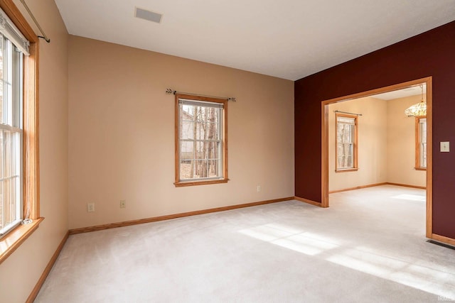 spare room with light colored carpet and a chandelier