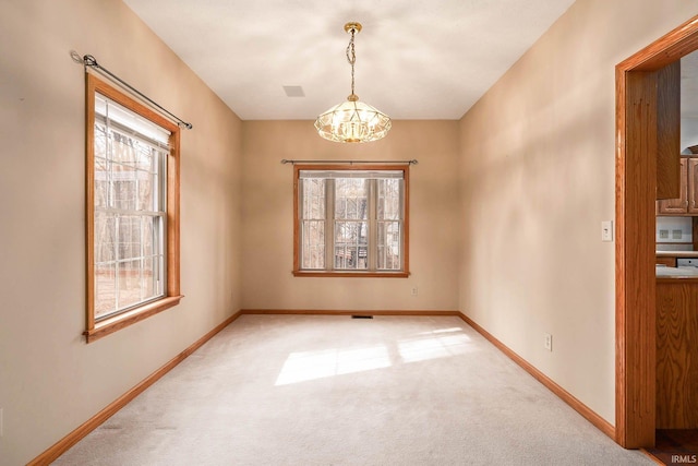 spare room featuring a healthy amount of sunlight, a notable chandelier, and carpet flooring