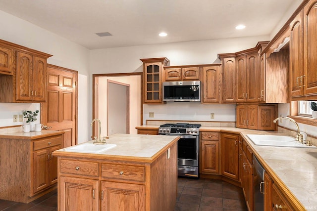 kitchen with appliances with stainless steel finishes, tile countertops, a center island, and sink