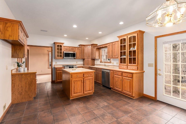 kitchen featuring a chandelier, hanging light fixtures, appliances with stainless steel finishes, a wealth of natural light, and a kitchen island with sink