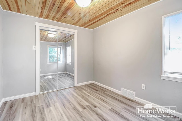 unfurnished bedroom featuring light hardwood / wood-style flooring, wooden ceiling, and a closet