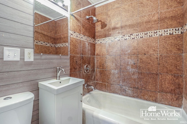 full bathroom featuring vanity, tiled shower / bath, and toilet