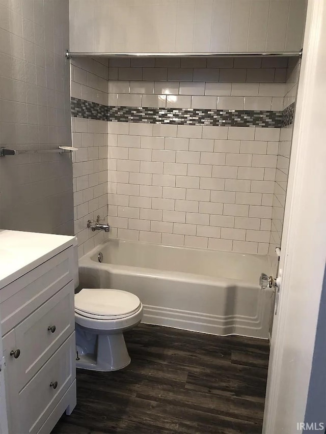 full bathroom featuring wood-type flooring, toilet, tiled shower / bath combo, and vanity