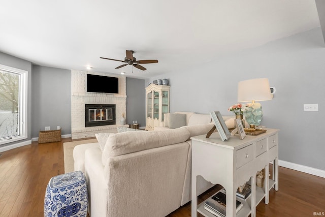 living room featuring a fireplace, dark hardwood / wood-style floors, and ceiling fan