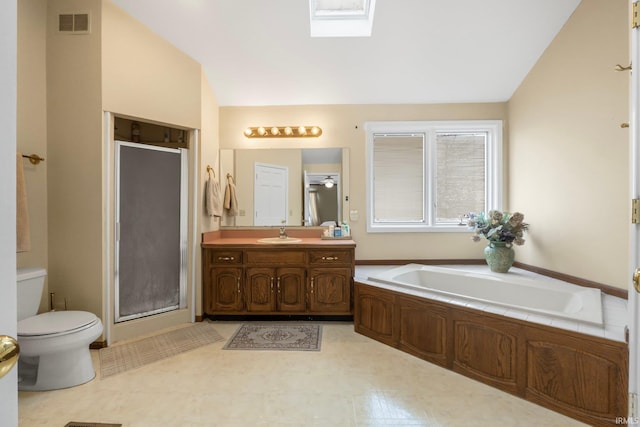 full bathroom with vanity, toilet, shower with separate bathtub, and vaulted ceiling with skylight