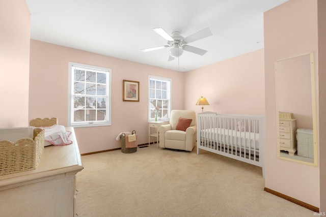 bedroom with multiple windows, a nursery area, ceiling fan, and carpet