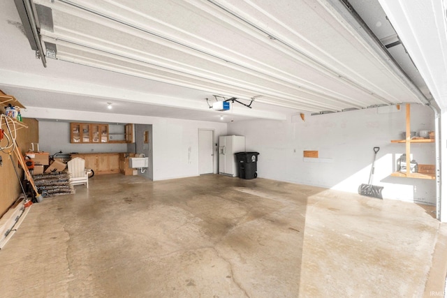 garage with sink, a garage door opener, and white fridge with ice dispenser