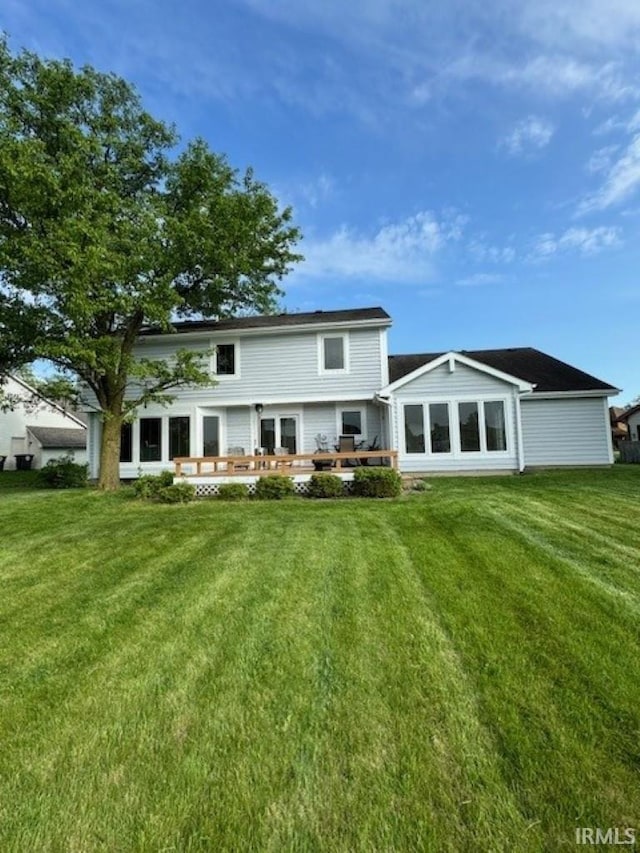 rear view of property featuring a deck and a lawn