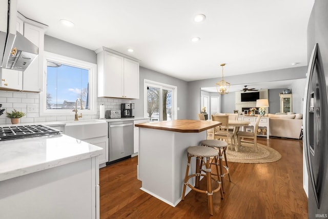 kitchen with white cabinetry, sink, dark hardwood / wood-style flooring, a center island, and stainless steel appliances