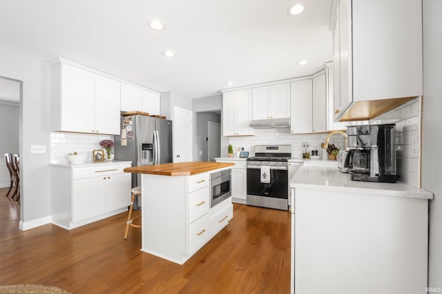 kitchen with white cabinetry, a center island, appliances with stainless steel finishes, dark hardwood / wood-style flooring, and a kitchen breakfast bar