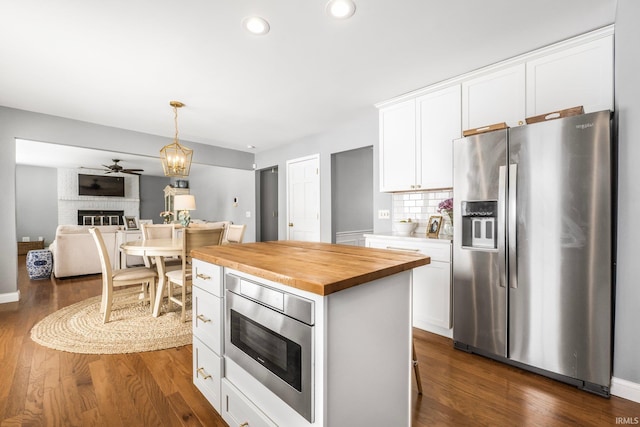 kitchen featuring appliances with stainless steel finishes, a fireplace, butcher block countertops, and white cabinets