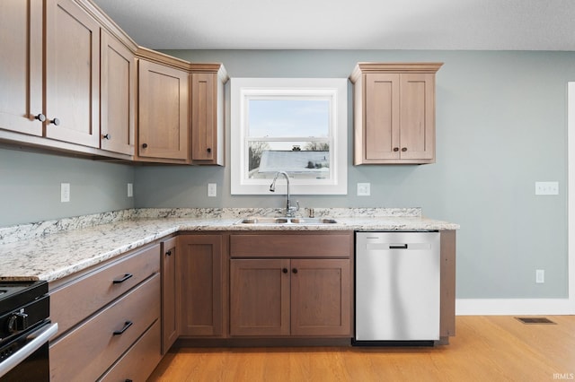 kitchen featuring dishwasher, sink, stove, light stone countertops, and light wood-type flooring