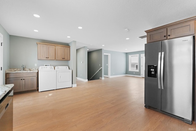 washroom with sink, washing machine and dryer, and light hardwood / wood-style floors