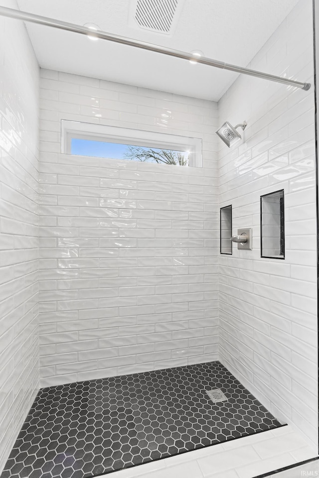 bathroom with a healthy amount of sunlight and a tile shower