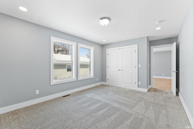 unfurnished bedroom featuring light carpet and a closet