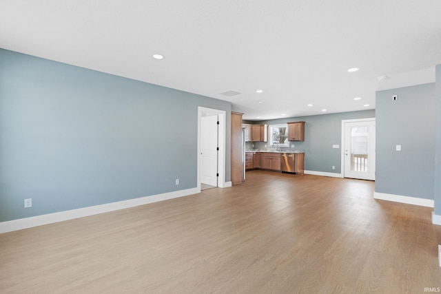 unfurnished living room featuring sink and light wood-type flooring