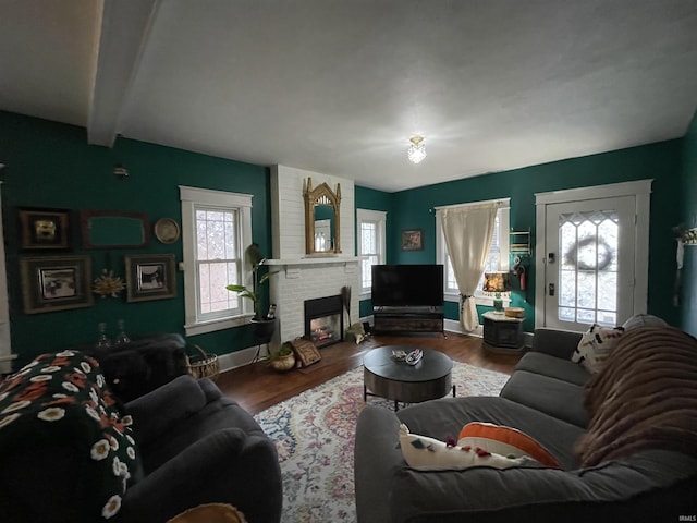 living room featuring a fireplace, beamed ceiling, and wood-type flooring