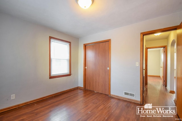 unfurnished bedroom featuring dark hardwood / wood-style flooring and a closet