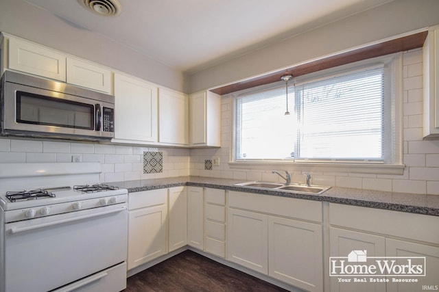 kitchen with tasteful backsplash, white cabinetry, sink, and gas range gas stove