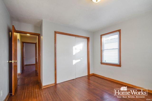 unfurnished bedroom with dark hardwood / wood-style flooring and a closet