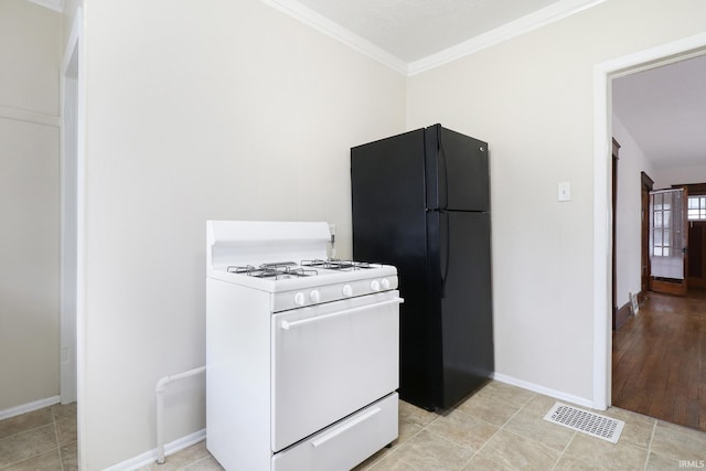 kitchen with black fridge, ornamental molding, white gas range, and light tile patterned floors