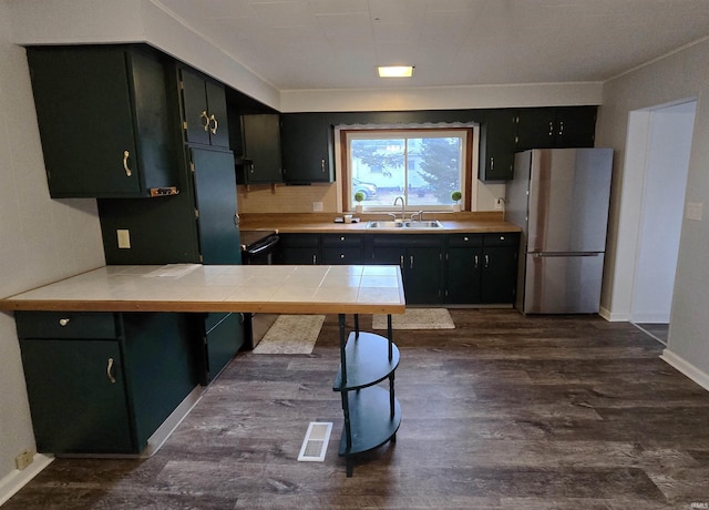 kitchen with sink, tasteful backsplash, stainless steel fridge, dark hardwood / wood-style flooring, and kitchen peninsula