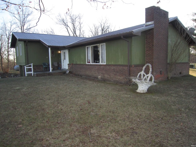 view of front of house featuring brick siding, a front yard, and a chimney