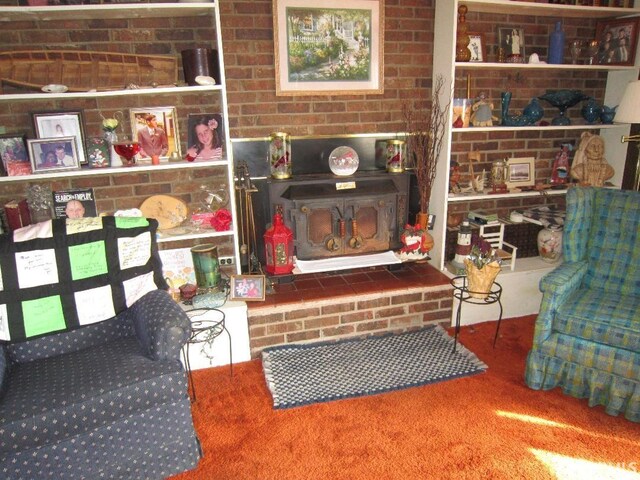 living area featuring carpet floors, brick wall, and a wood stove