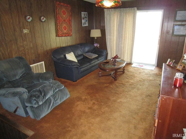 living area with carpet flooring, visible vents, and wood walls