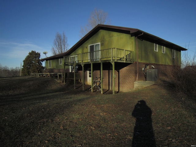 view of side of home featuring brick siding, central AC unit, and a deck