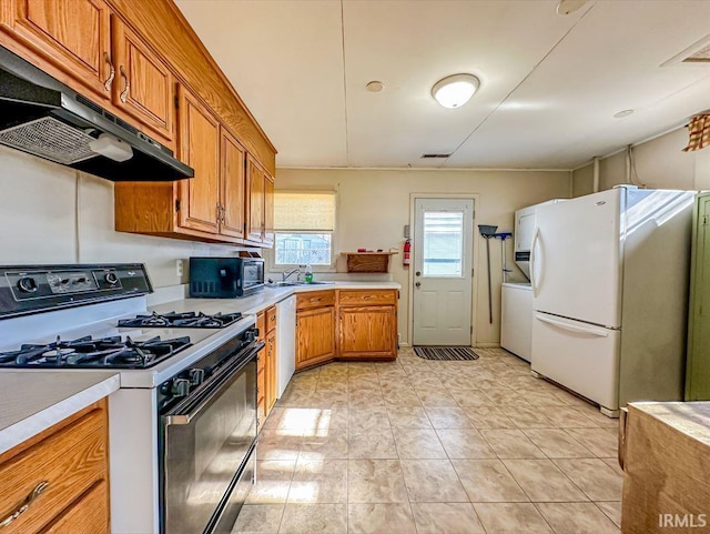 kitchen featuring washer / dryer, sink, dishwasher, white fridge, and gas range oven