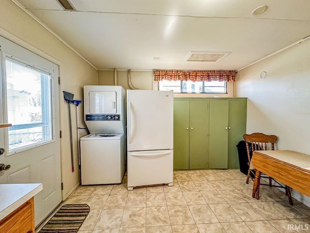 kitchen featuring stacked washer and dryer, light tile patterned floors, green cabinets, white refrigerator, and ornamental molding